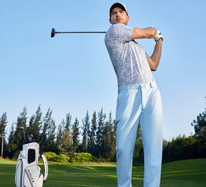 The model, wearing a Popular Heather Print Polo, strikes a follow-through pose after hitting the ball on the golf course.