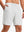Front lower body shot of model wearing white breathable running shorts with 4 zipper pockets