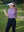 Model in lilac women's performance solid polo holding a golf club outdoors