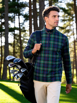 Outdoor shot of a model carrying a golf bag, wearing the dark plaid full print lightweight quarter zip pullover with a relaxed fit