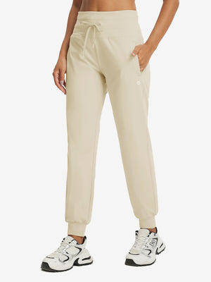 Model wearing women's stretch fleece lined water resistant joggers in light khaki, showcasing the front lower body view.