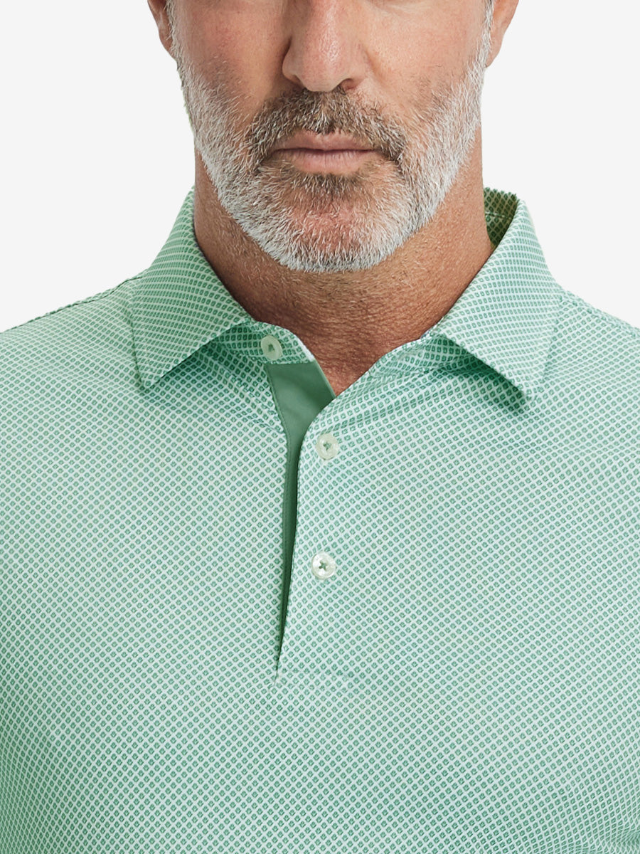 Close-up from nose to chest, showing collar and fabric pattern detail of the green plant polo shirt.