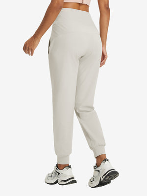 Model wearing women's stretch fleece lined water resistant joggers in oyster gray, showing the back lower body view.