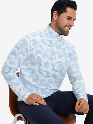 Model seated on chair, wearing full print quarter zip pullover in sky blue camo, casual upper body view.