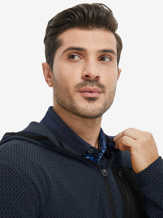Model holding collar with one hand, wearing full zip fleece hoodied jacket in navy.