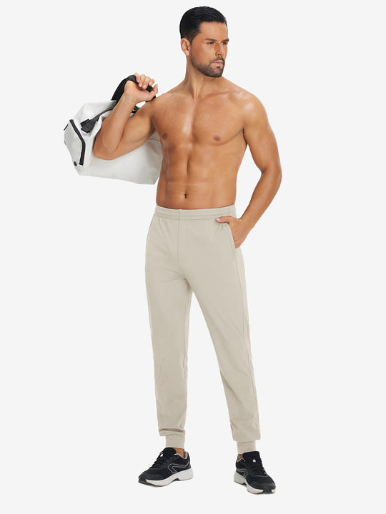 Model holding tennis racket wearing lightweight traning track pants in khaki.