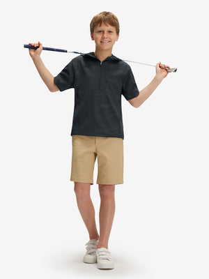 Full-body shot of model holding a golf club in dark grey water-resistant short sleeve q-zip hoodie for boys