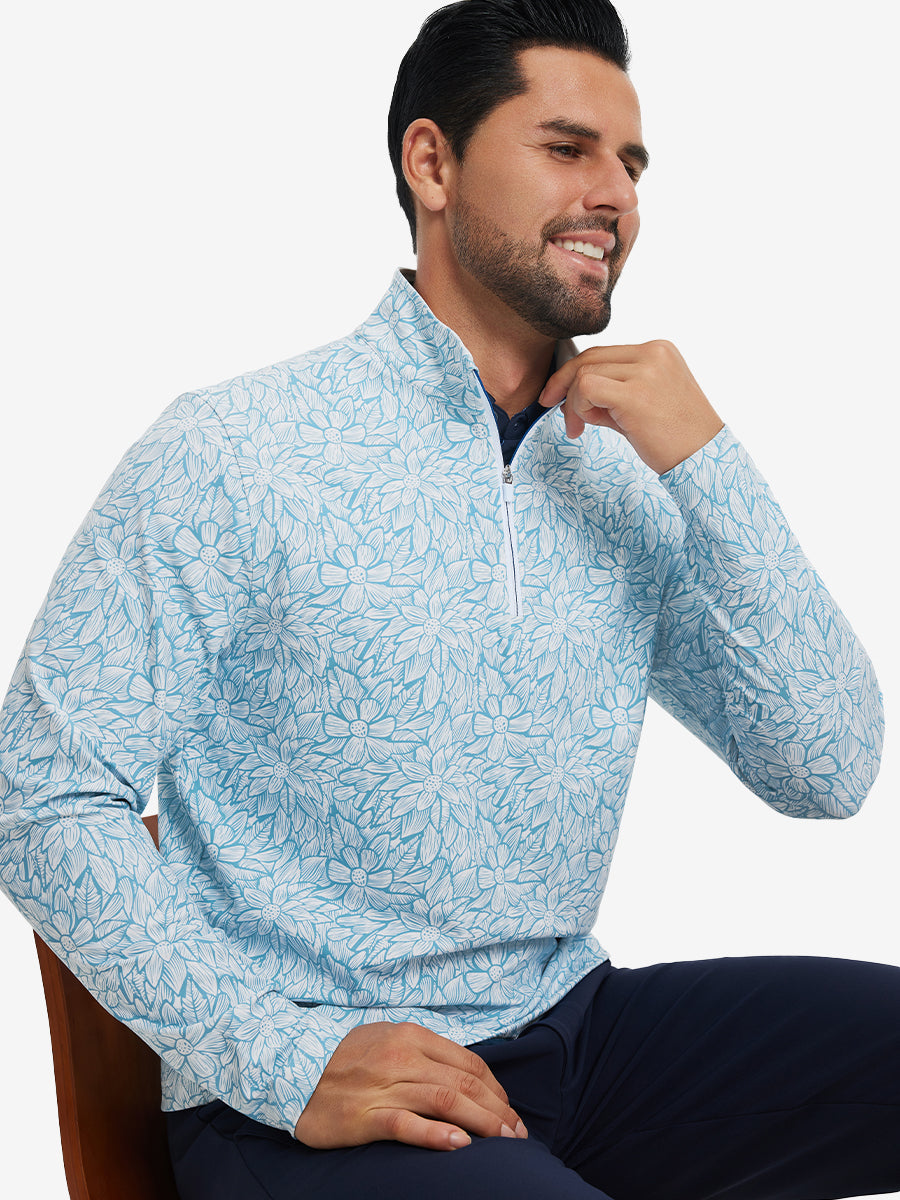 Model seated on chair, wearing full print quarter zip pullover in blue artichoke, casual upper body view.