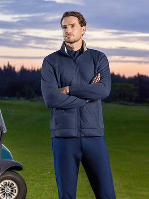 Model standing on course with hands clasped, golf fleece winter puffer jackets styled in navy