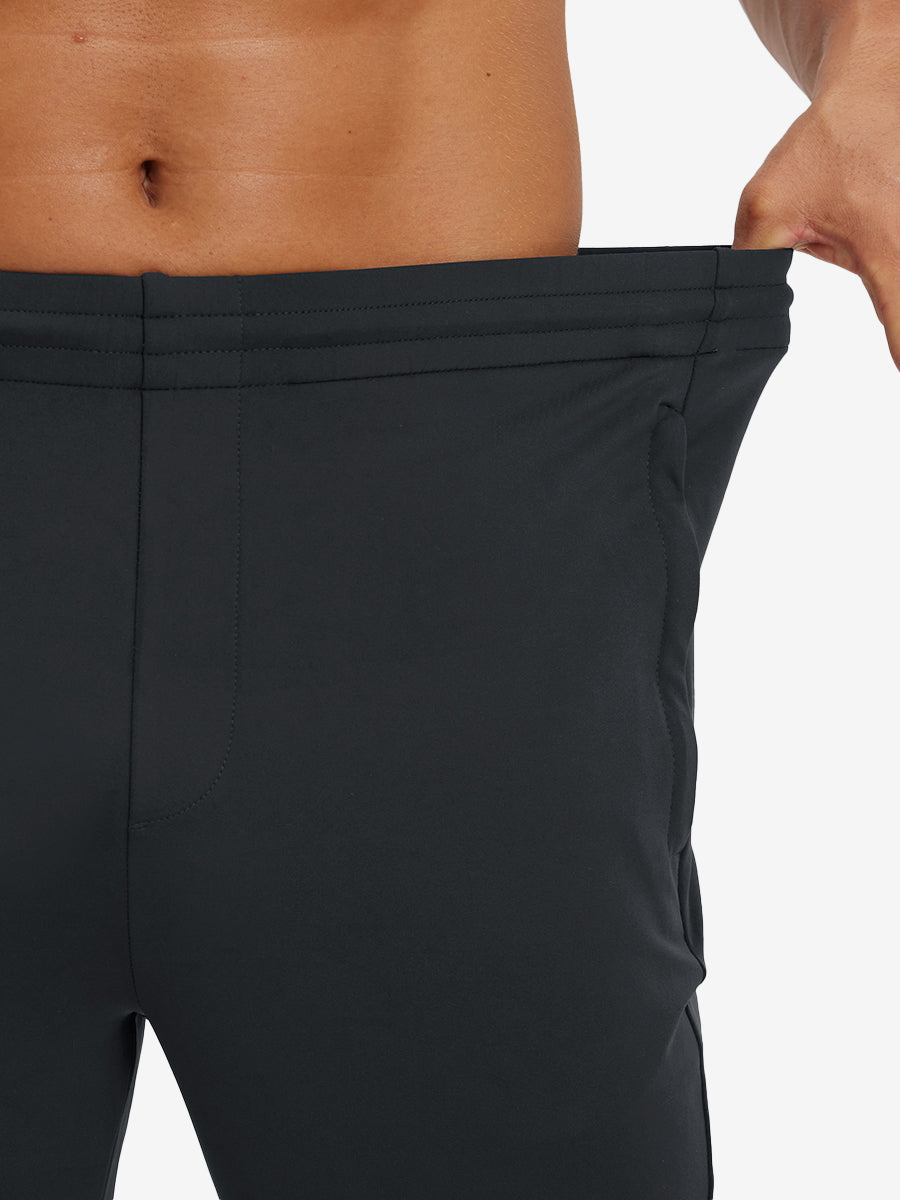 Model stretching waistband to show fit of lightweight traning track pants in black.