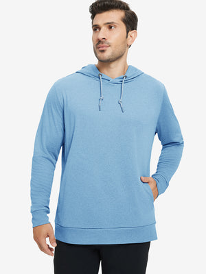 Model with one hand in pocket, wearing classic heather pullover hoodie in light blue melange, relaxed look.