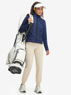 Model carrying a golf bag, wearing women's lightweight fleece-lined puffer jacket in navy.