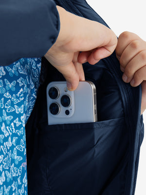 Close detail of hands inside pockets of boys windproof puffer jacket with pockets in dark blue.