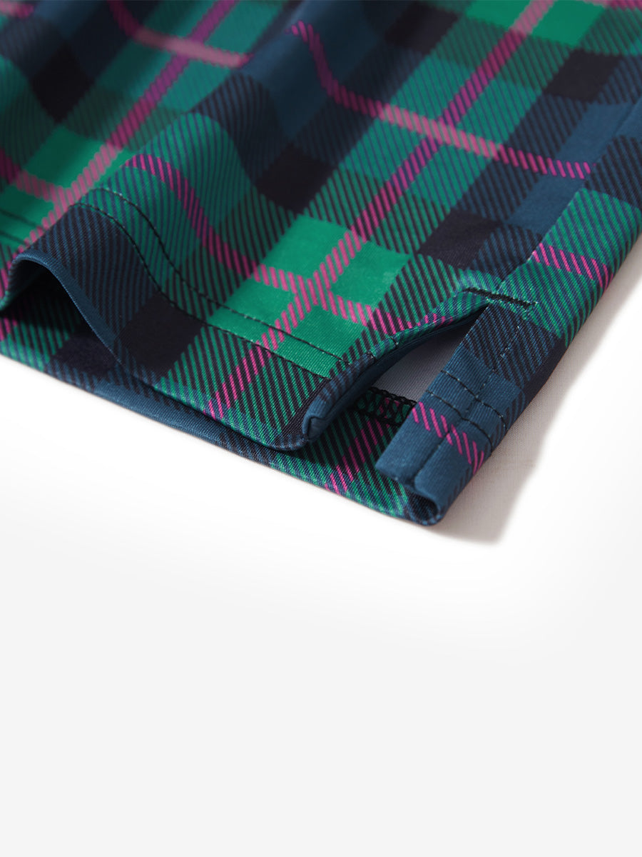Hem slit detail of the dark plaid lightweight print long sleeve polo, showing fine stitching and finish.