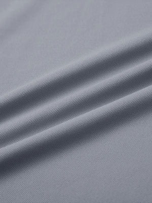 Close-up of light grey ventilated pique performance polo fabric texture.