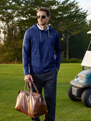 Model in cobalt heather fleece hoodies pullover holding a bag on the golf course