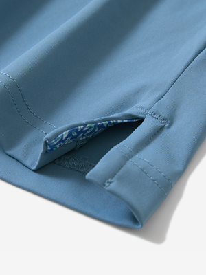 Detail of the side vent hem on the misty blue everyday classic solid polo, showing the split hem feature
