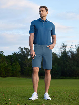 Model standing on course with one hand in pocket, wearing 4-way stretch performance solid shorts in grayish blue